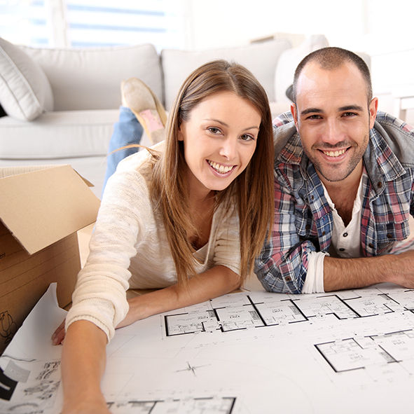 pareja en el suelo mirando un plano de obras